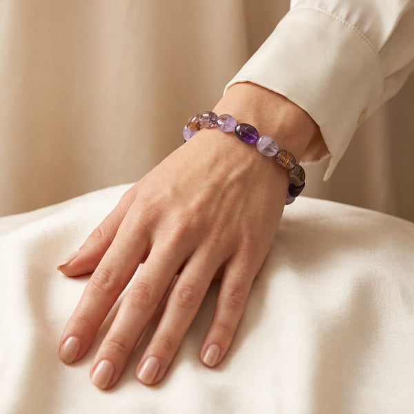 Bracelet Super Seven porté par une femme, pierres roulées mauves aux inclusions dorées
