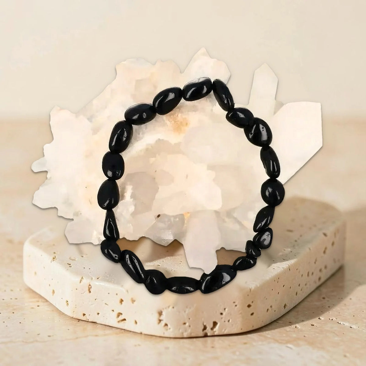 Bracelet en tourmaline noire véritable, galets roulés photographiés sur un amas de quartz