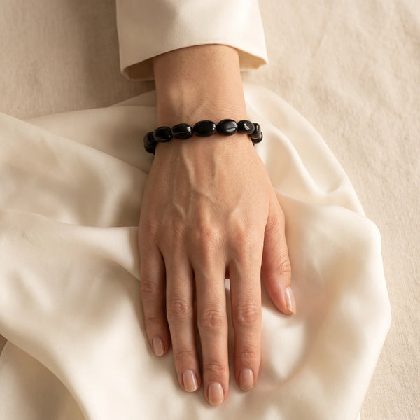 Bracelet tourmaline noire porté au poignet d'une femme, pierres roulées noires brillantes