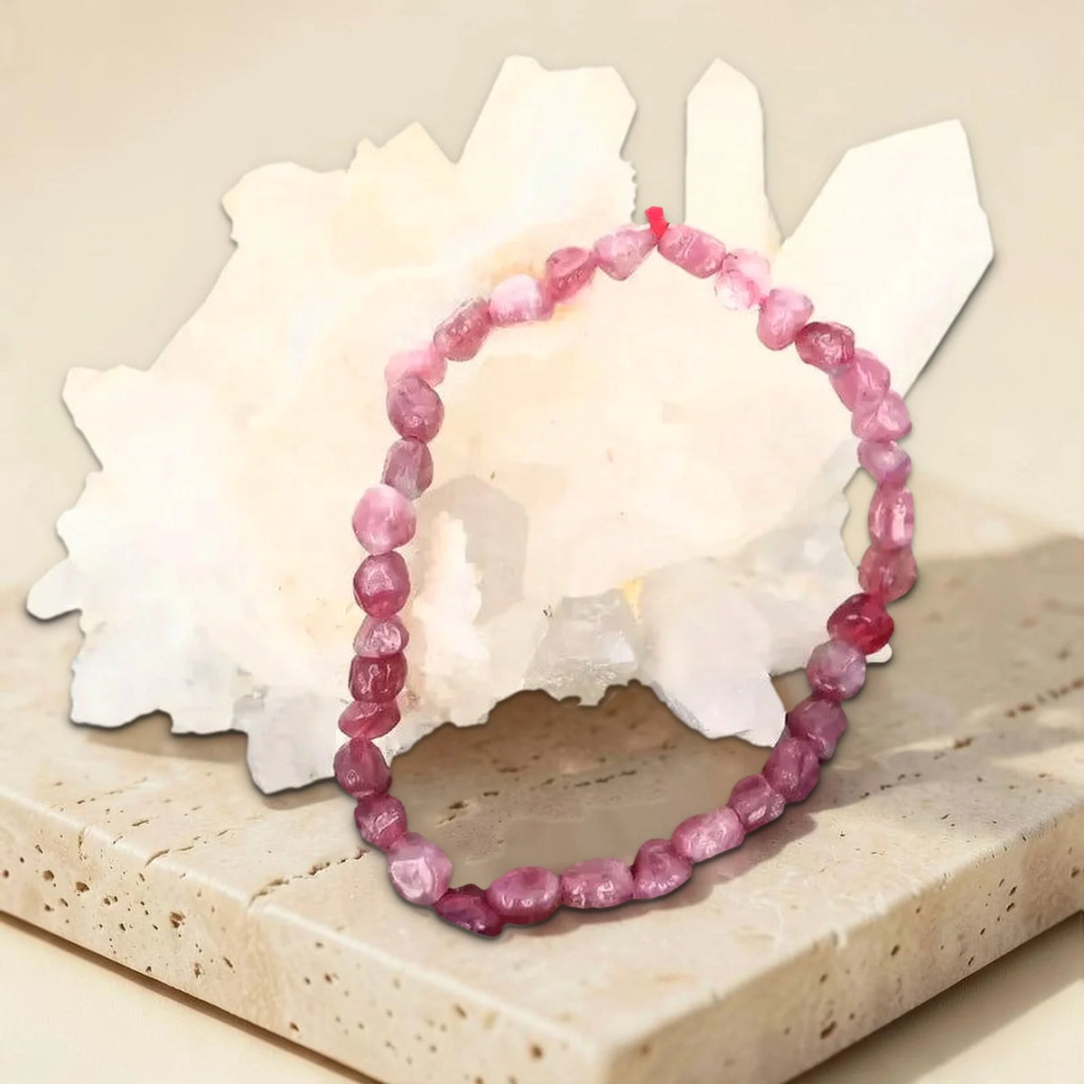 Bracelet pierre roulée tourmaline rose, photo réelle sur travertin avec un amas de quartz