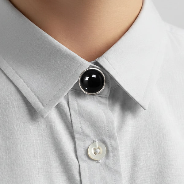Cache bouton en obsidienne noire clipsé au col fermé d'une chemise gris clair