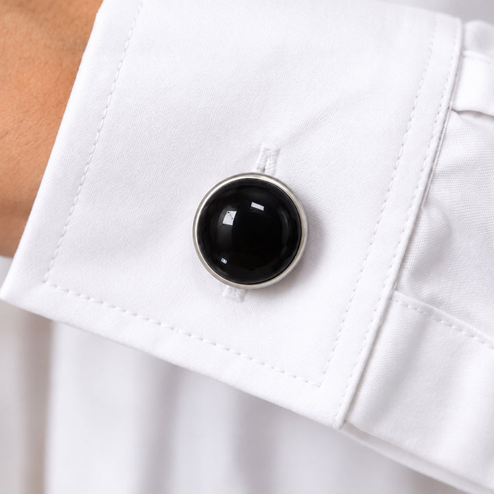 Cache bouton en obsidienne noire clipsé sur le bouton du poignet d'une chemise blanche