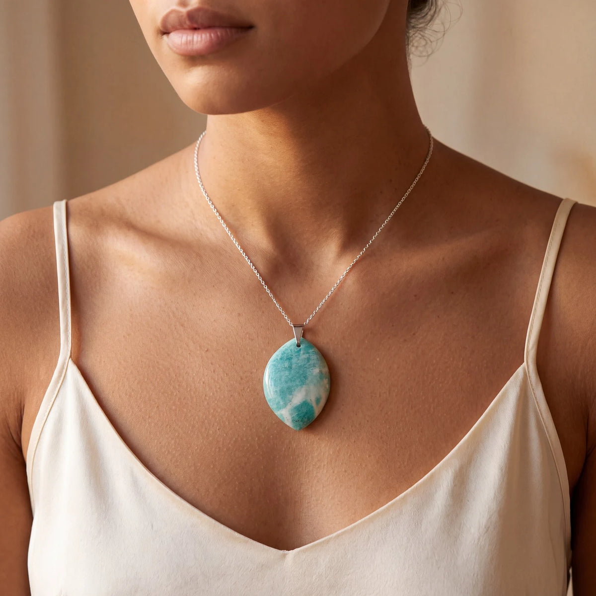 Collier amazonite femme, pendentif plat forme libre bleu-vert porté sur un haut crème
