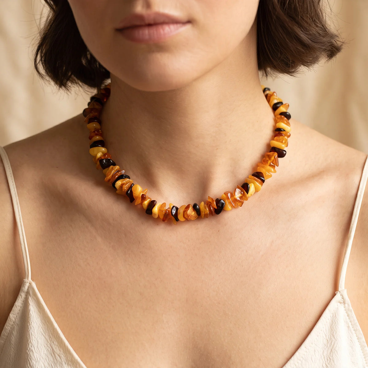 Collier ras de cou en ambre multicolore porté par une femme, perles baroques naturelles