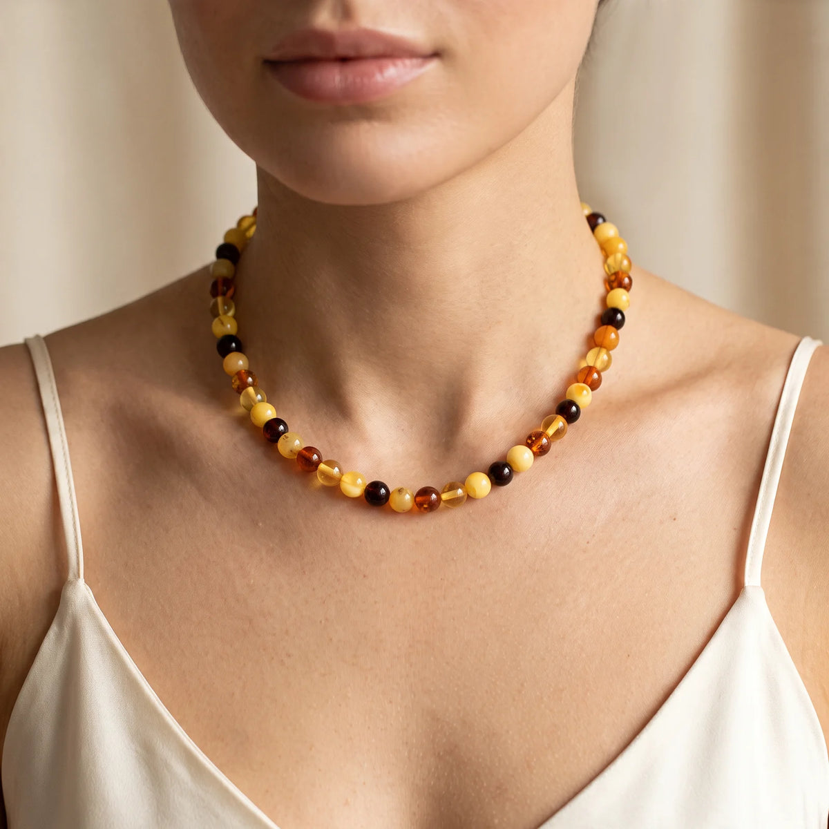 Collier ras de cou en ambre perles rondes multicolores porté par une femme