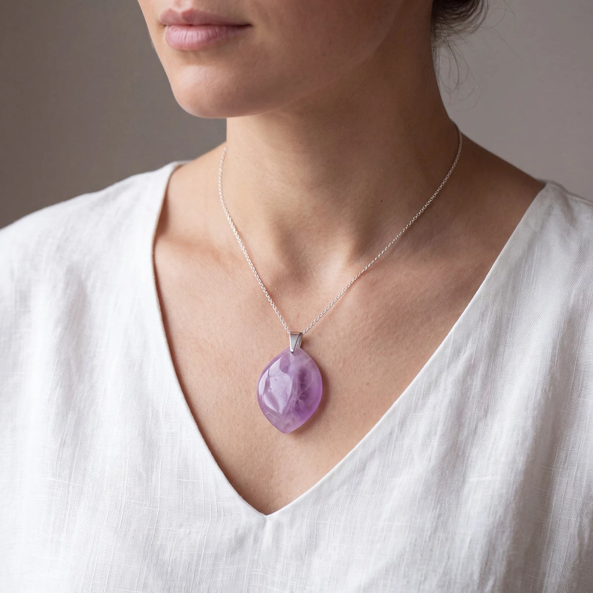 Pendentif améthyste femme, pierre plate violette forme libre portée sur un caraco crème