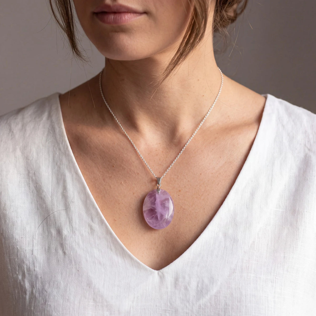 Pendentif ovale en améthyste véritable porté par une femme, pierre violette sur chaîne argentée