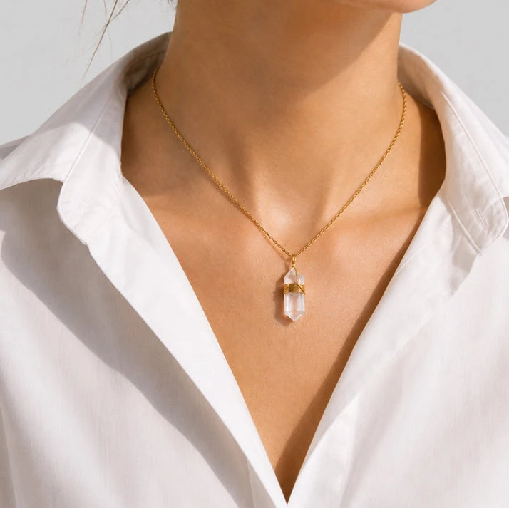 Collier cristal de roche porté sur chemise blanche, pendentif pointe transparente