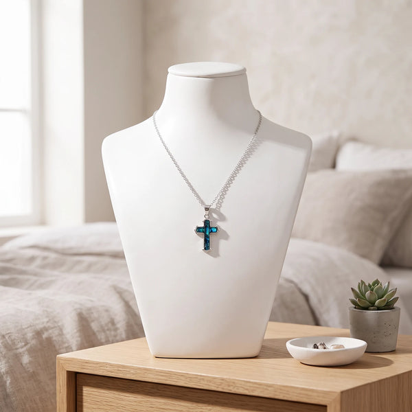 Collier croix bleu en nacre naturelle porté sur un buste, pendentif croix sur chaîne argentée