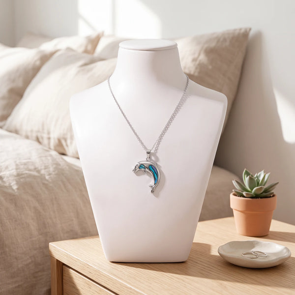 Collier dauphin bleu en nacre naturelle porté sur un buste, pendentif dauphin sur chaîne argentée