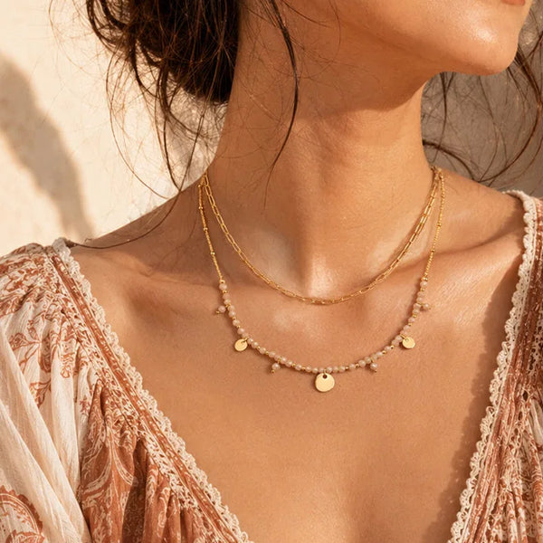 Collier doré femme en pierre de lune rose porté par une femme, chaîne et perles dorées