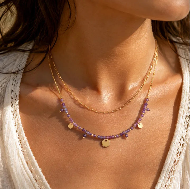 Collier double rang en améthyste porté par une femme, chaîne et perles dorées