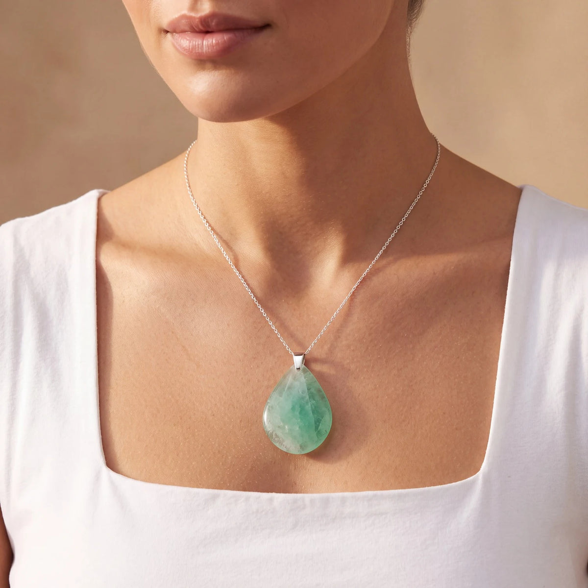 Pendentif goutte en fluorine verte porté par une femme, pierre plate translucide