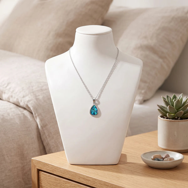 Collier goutte bleu en nacre naturelle porté sur un buste, pendentif goutte sur chaîne argentée