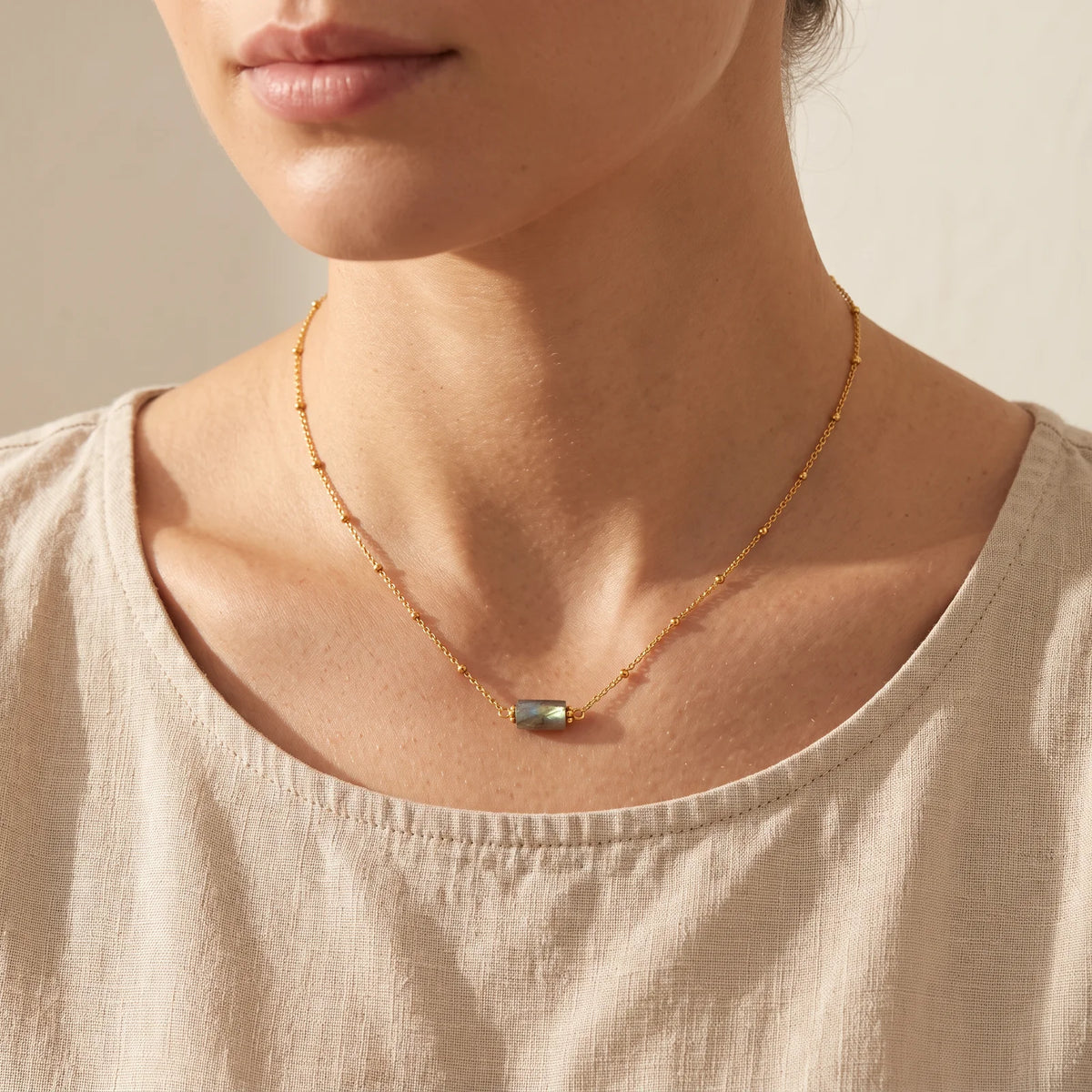 Collier labradorite femme LUMIA® porté par une femme, tube en labradorite sur chaîne dorée