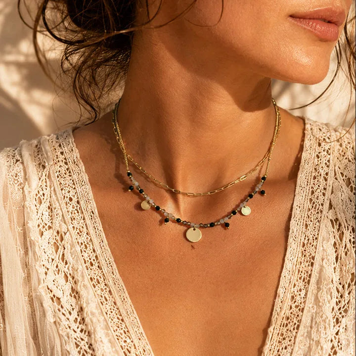 Collier multi rangs en tourmaline noire et quartz fumé porté par une femme, chaîne et perles dorées