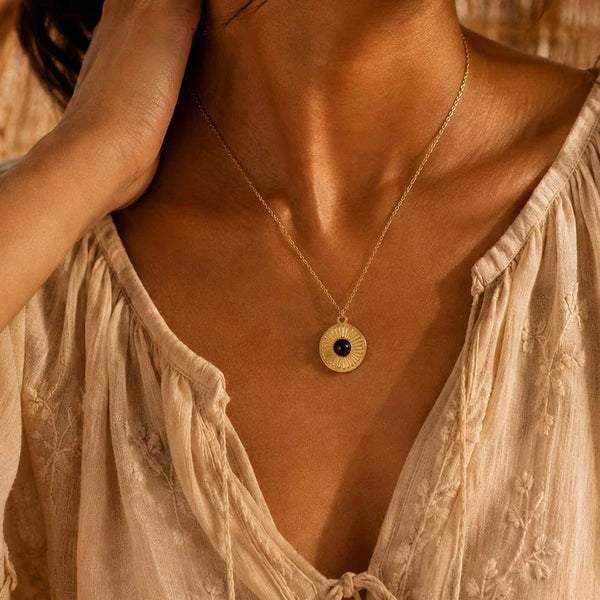 Collier onyx SOLAYA® porté par une femme, médaille soleil sur chaîne fine