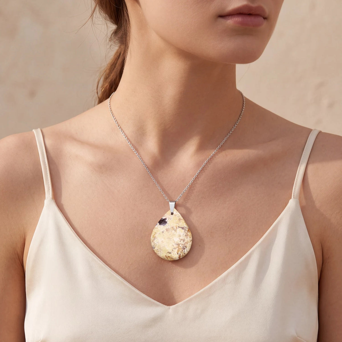 Pendentif opale naturelle porté par une femme, goutte verte plate sur chaîne fine