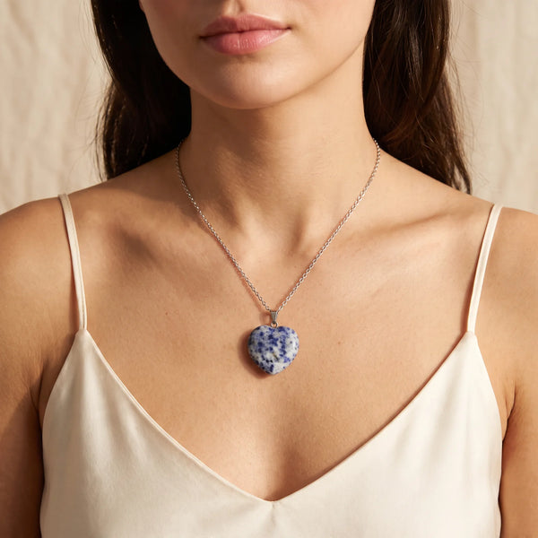 Collier pendentif cœur en sodalite bleue et blanche porté par une femme, chaîne argentée