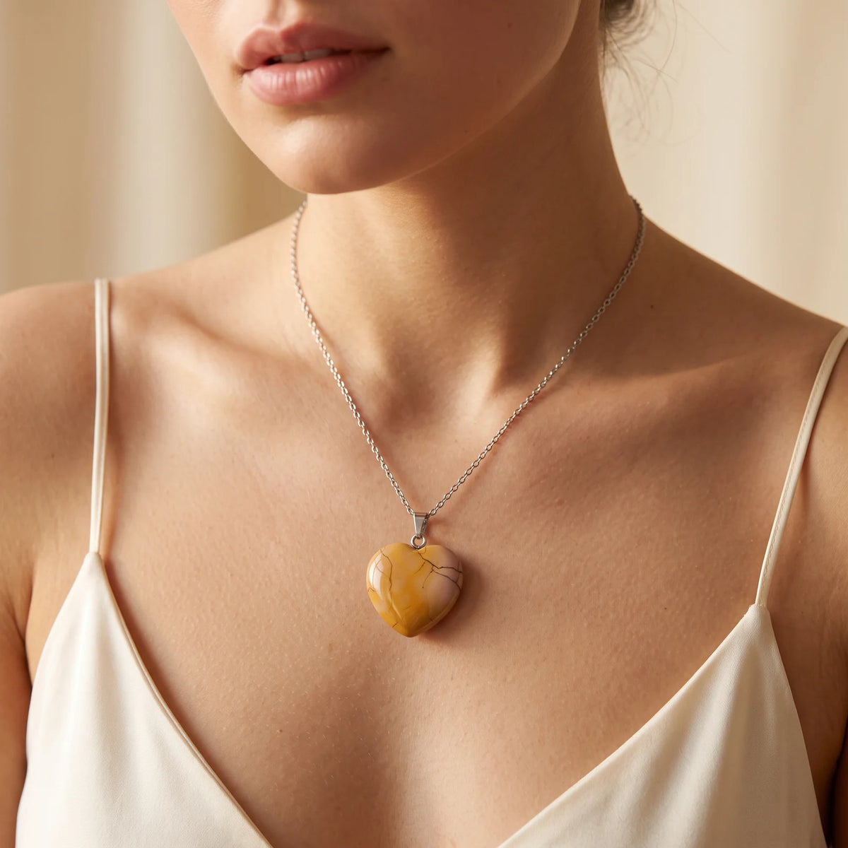 Collier pendentif cœur en mokaïte jaune naturelle porté par une femme