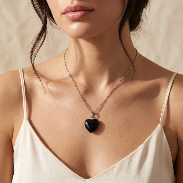 Collier pendentif cœur en onyx noir naturel porté par une femme, chaîne argentée