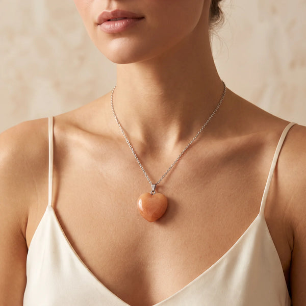 Collier pendentif cœur en aventurine orange naturelle porté par une femme, chaîne argentée
