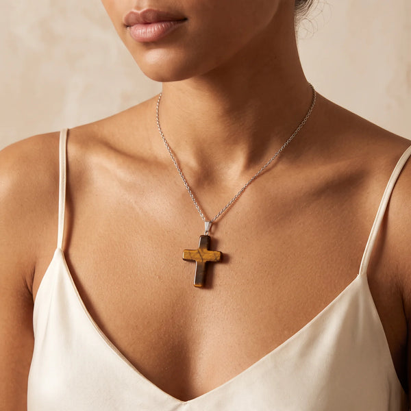 Collier pendentif croix en œil de tigre naturel porté par une femme, chaîne argentée