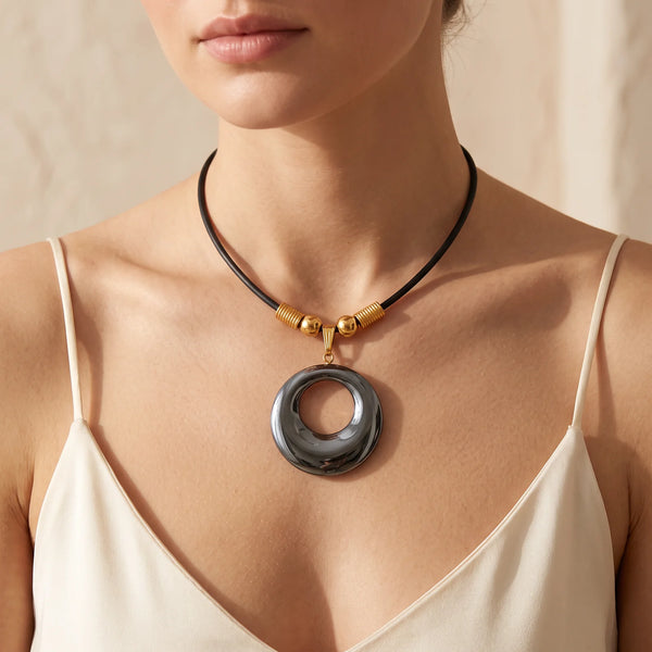 Collier pendentif donut en hématite naturelle porté par une femme, cordon noir 43 cm