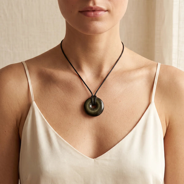 Collier pendentif donut en obsidienne dorée naturelle porté par une femme, cordon noir
