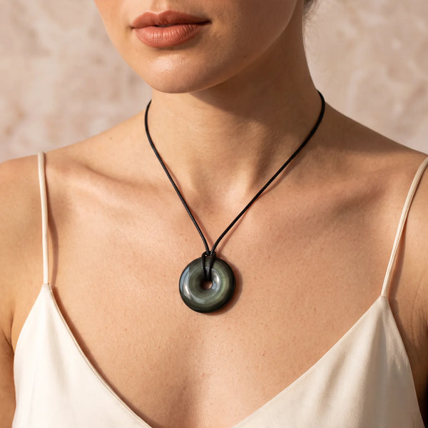 Collier pendentif donut en obsidienne œil céleste naturelle porté par une femme, cordon noir