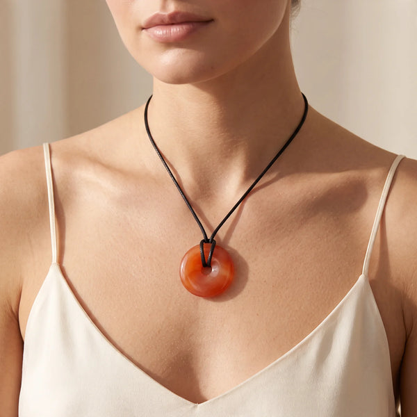 Collier pendentif donut en cornaline naturelle porté par une femme, cordon noir ciré