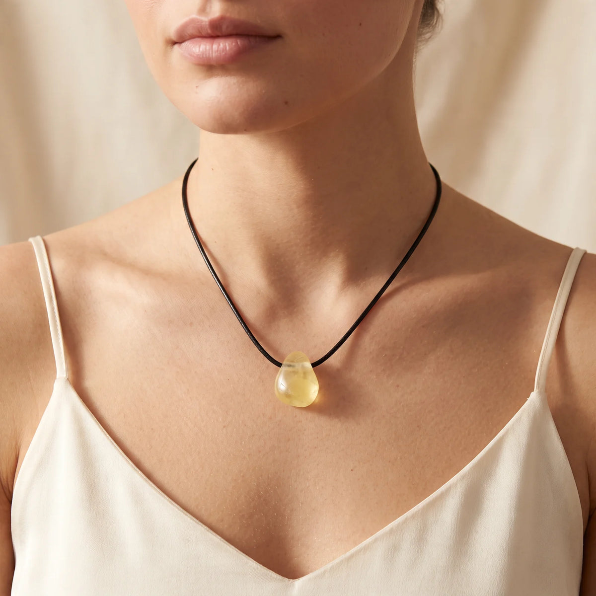 Collier pendentif pierre percée en calcite jaune naturelle porté par une femme, cordon noir