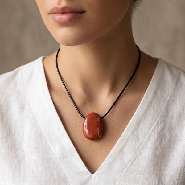Collier pendentif rouge en jaspe, pierre percée ovale portée par une femme