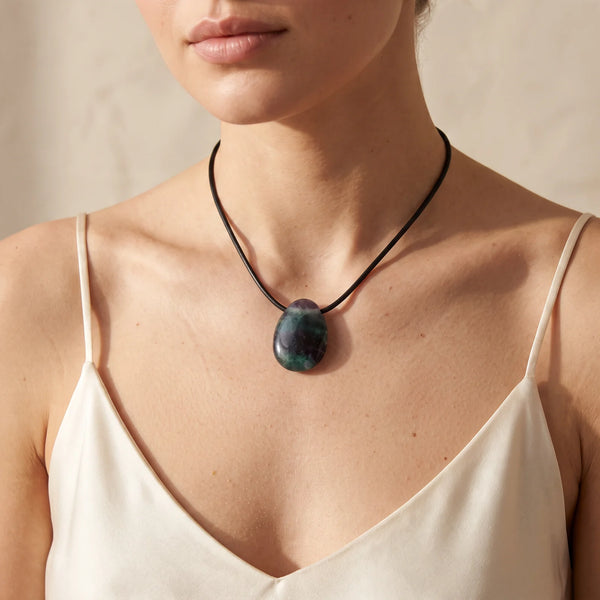 Collier pendentif goutte en fluorine multicolore porté par une femme, cordon noir