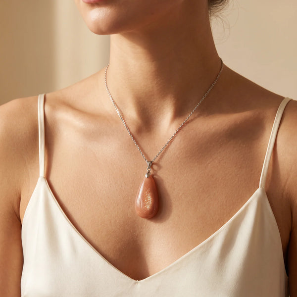 Collier pendentif goutte en pierre de soleil naturelle porté par une femme, chaîne argentée