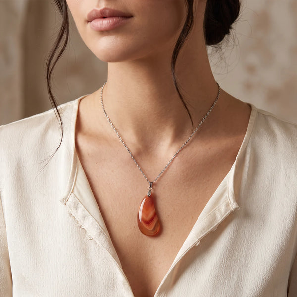 Collier pendentif goutte en agate rouge naturelle porté par une femme