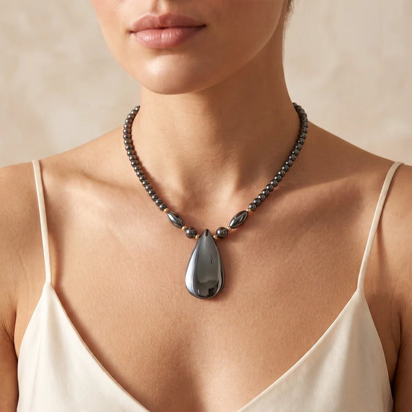 Collier pendentif goutte plate en hématite naturelle porté par une femme, perles d'hématite