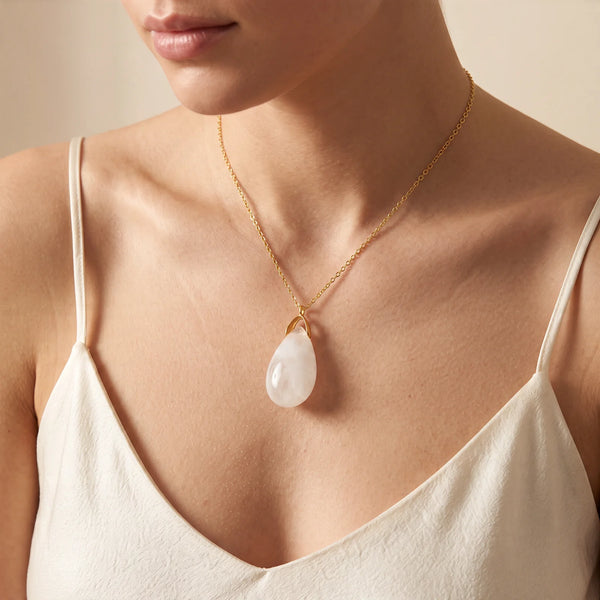 Collier pendentif larme en cristal de roche naturel porté par une femme, chaîne dorée