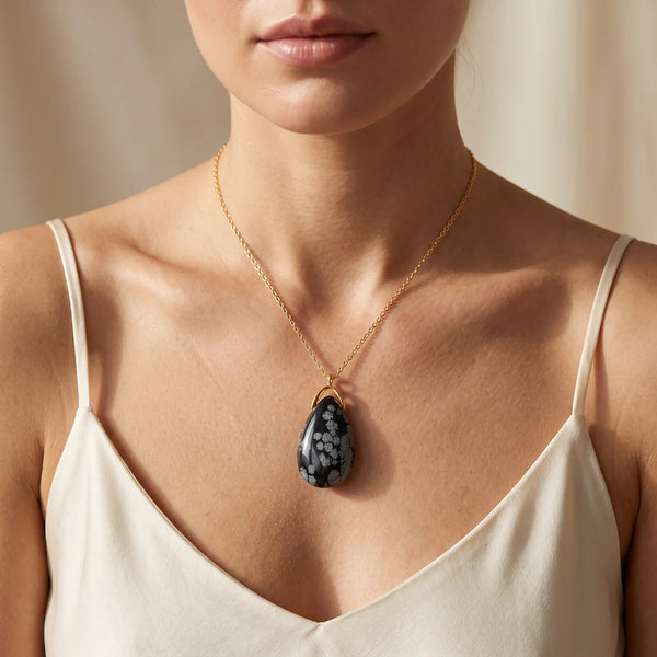 Collier pendentif larme en obsidienne neige naturelle porté par une femme, chaîne dorée