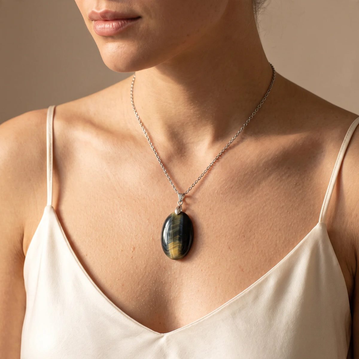 Collier pendentif ovale en œil de faucon naturel porté par une femme, bélière argentée