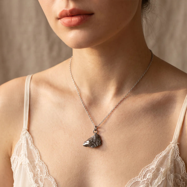 Collier pendentif fragment de météorite naturelle porté par une femme, chaîne argentée