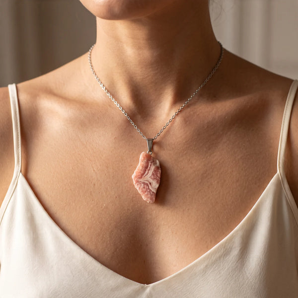 Collier pendentif pierre brute en rhodochrosite rose porté par une femme