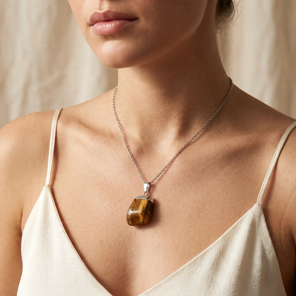 Collier pendentif pierre roulée en œil de tigre naturel porté par une femme