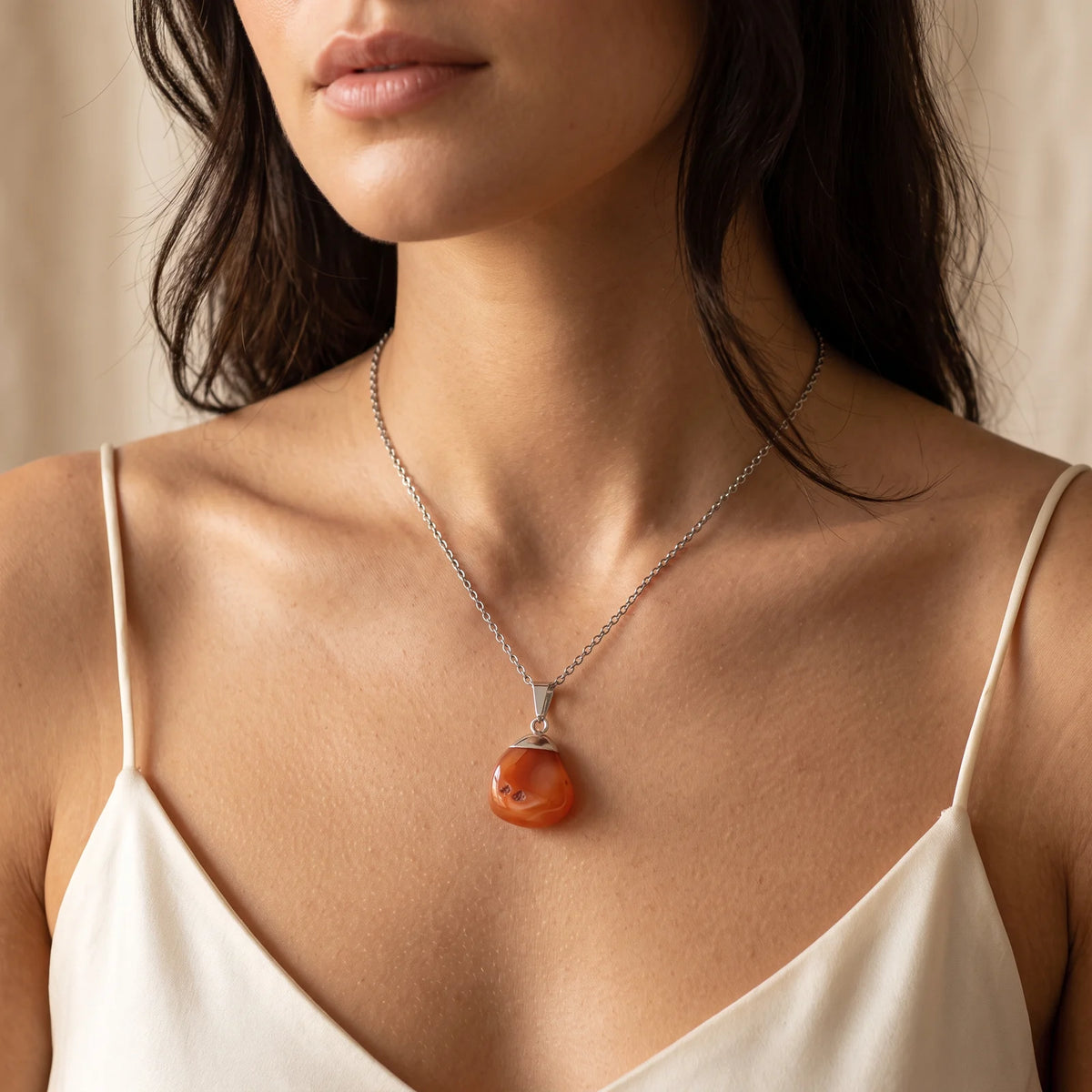 Collier pendentif pierre roulée en cornaline orange porté par une femme