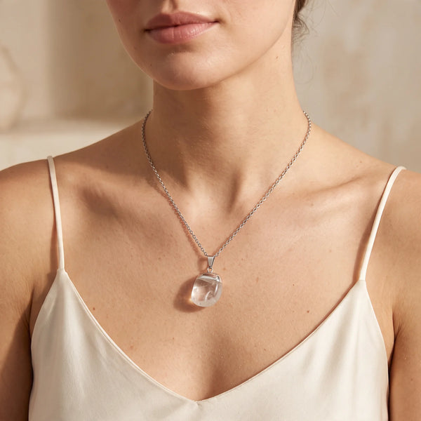 Collier pendentif pierre roulée en cristal de roche naturel porté par une femme, chaîne argentée