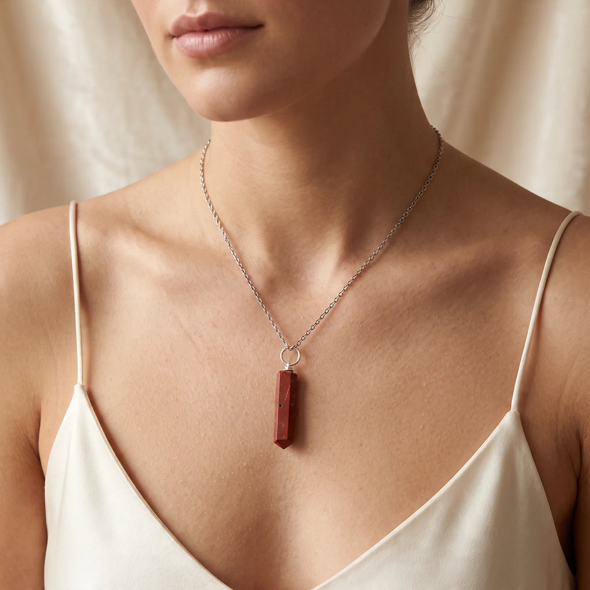Collier pendentif pointe en jaspe rouge naturel porté par une femme, chaîne argentée