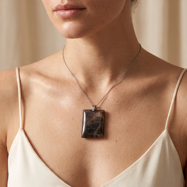 Collier pendentif rectangle en pierre de lune noire naturelle porté par une femme