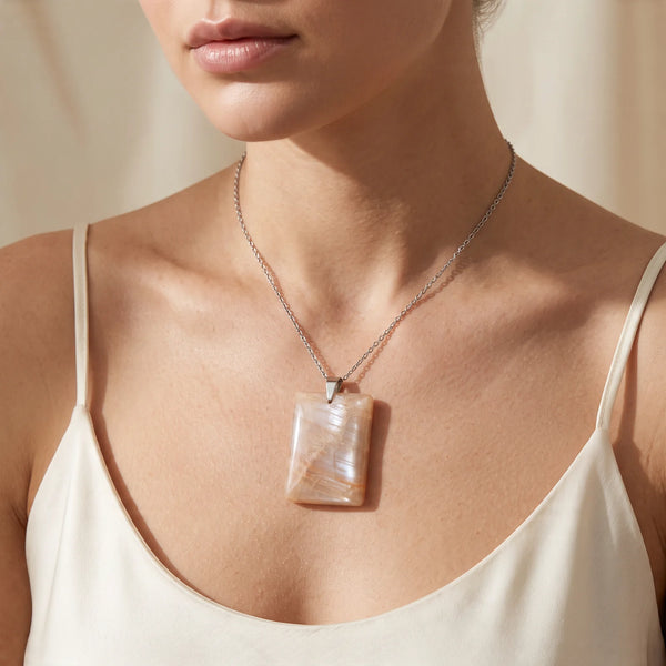 Collier pendentif rectangle en pierre de lune orange naturelle porté par une femme