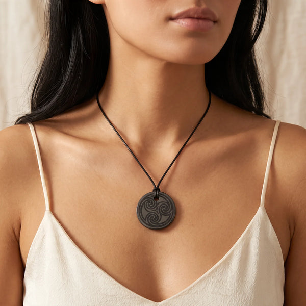Collier pendentif triskèle gravé en shungite naturelle porté par une femme, cordon noir