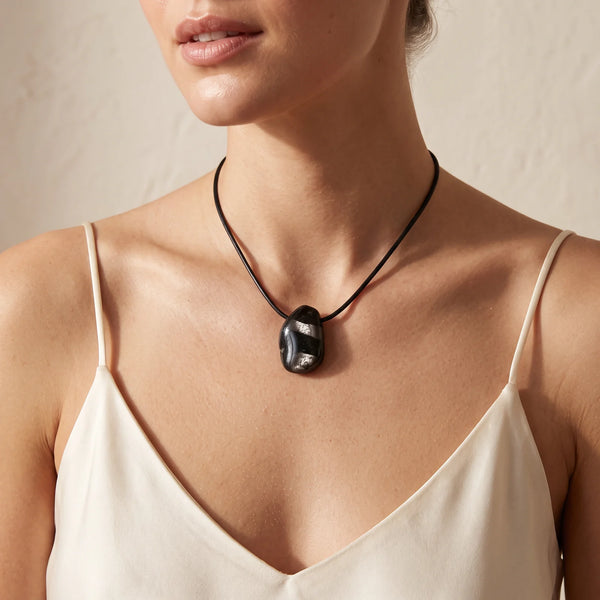 Collier pendentif pierre roulée percée en hypersthène noire naturelle porté par une femme, cordon noir